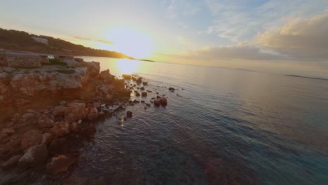 Fpv---Volando-Sobre-La-Playa-De-Kavouri-En-Vouliagmeni,-Grecia-Al-Atardecer