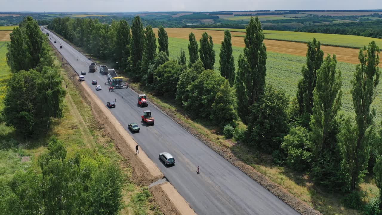 Road construction equipment. Asphalt paver, roller and truck on the road repair site during asphalting