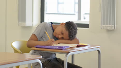 in school, boy writing in notebook, looking focused and thoughtful