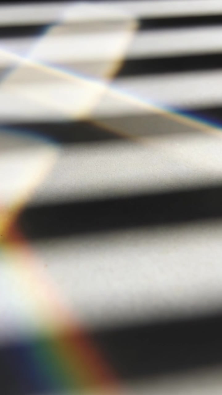 Video verticale: Spettro arcobaleno cangiante che scivola attraverso le persiane alla finestra dopo uno spostamento della telecamera, prisma.