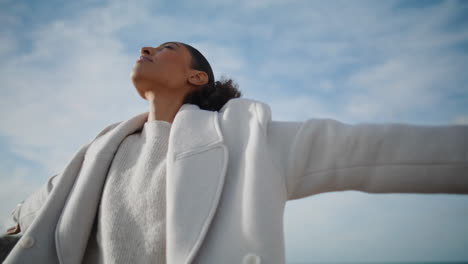 Cheerful-woman-open-arms-at-cloudy-sky-bottom-view.-Happy-african-american-pose