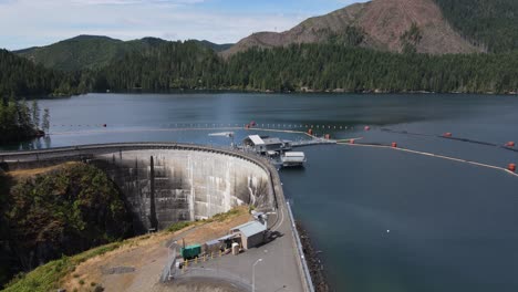 Slowly-passing-over-the-small-dam-on-Lake-Kokanee,-Olympic-Peninsula,-aerial