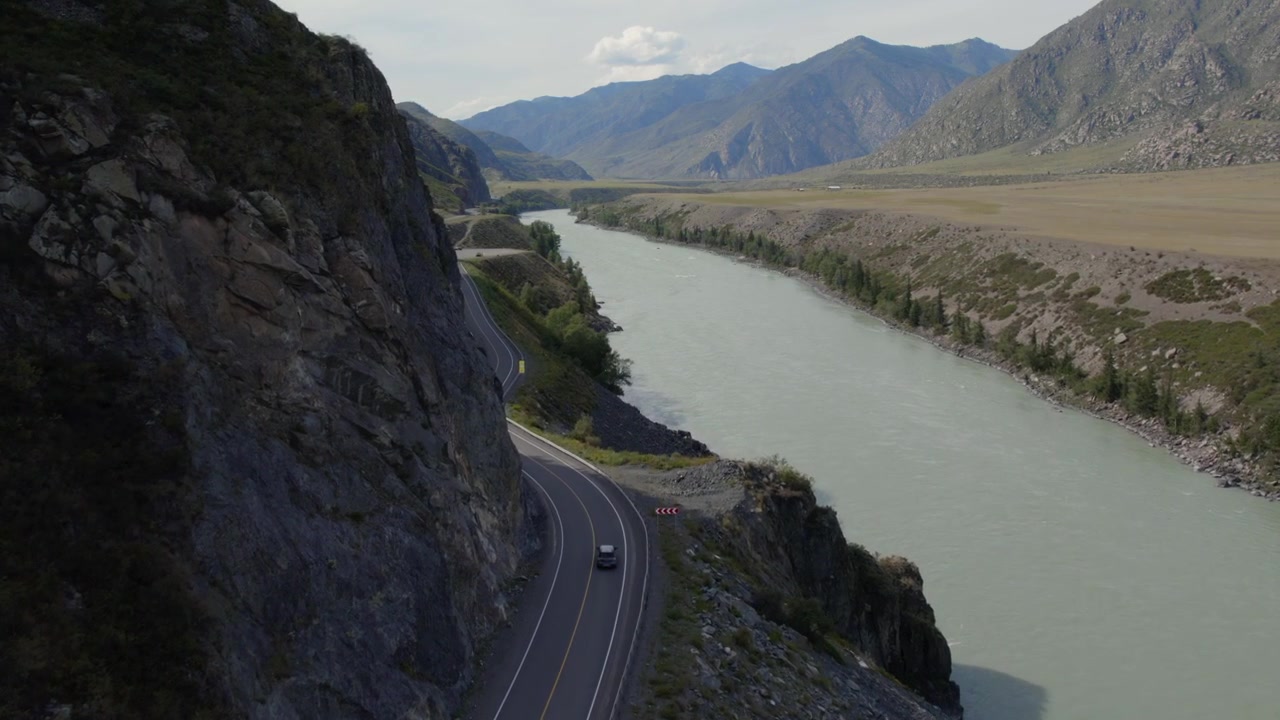 Filmato drone dell'autostrada Chuysky Trakt che serpeggia accanto al fiume Katun color turchese attraverso una valle montuosa rocciosa nella Repubblica dell'Altai, Russia, paesaggio di viaggio panoramico.
