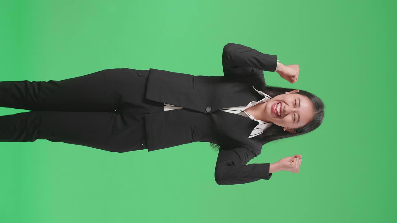 Happy Asian Business Woman Celebrating While Standing On Green Screen In The Studio