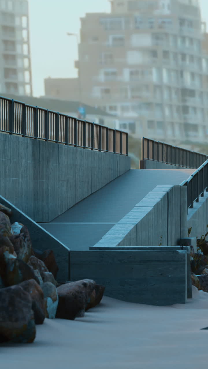 una rampa de hormigón que conduce a la playa con rocas y arena