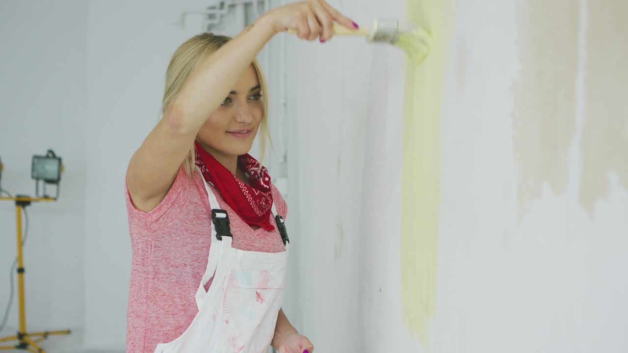 Smiling woman painting wall yellow