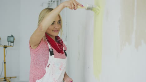 Smiling-woman-painting-wall-yellow