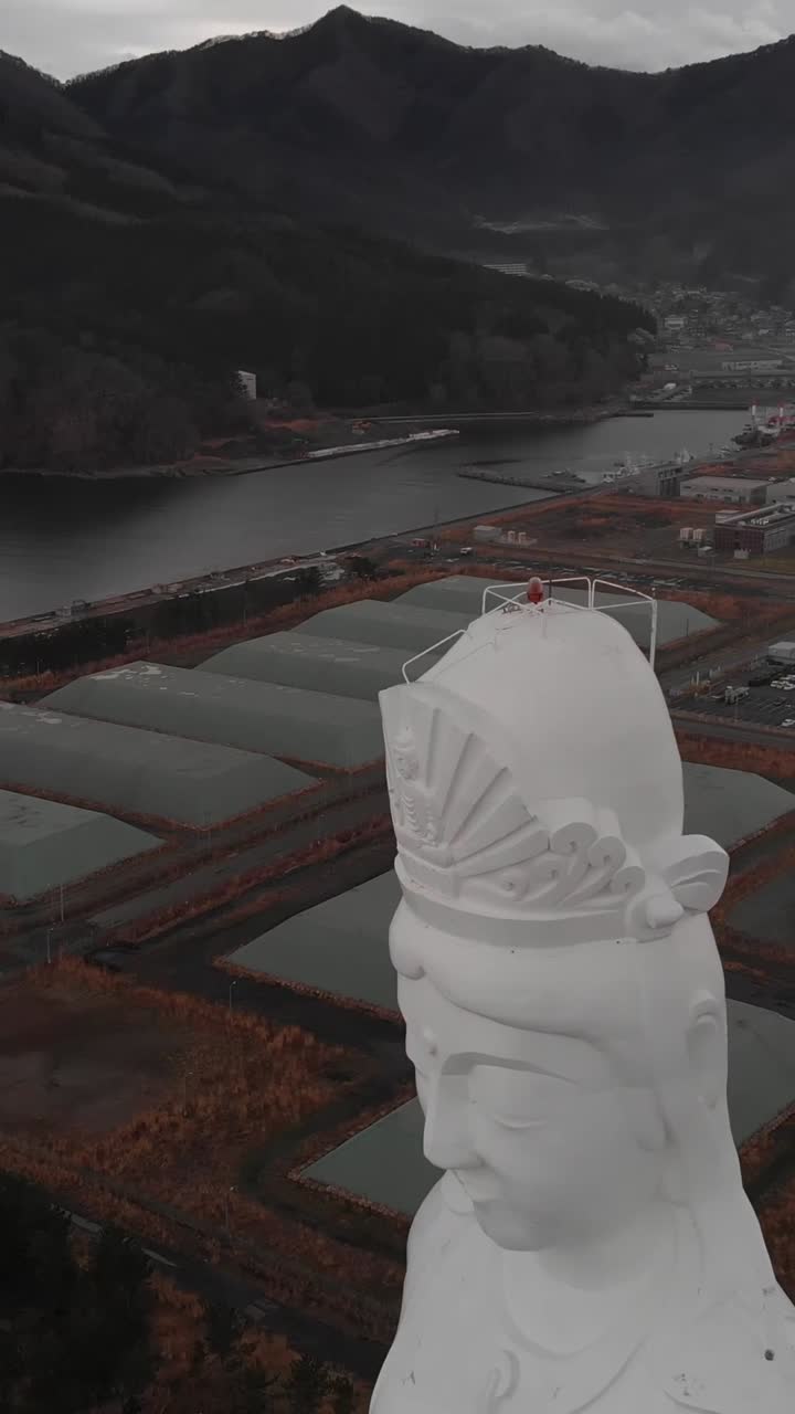 Pystysuuntainen ilmakuva läheltä Aizu Jibo Kannonin suurikokoisesta hengellisestä Mercy-patsaasta turistien kanssa Fukushimassa, Japanissa