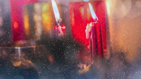 velas y decoración navideña combinadas con la nieve que cae
