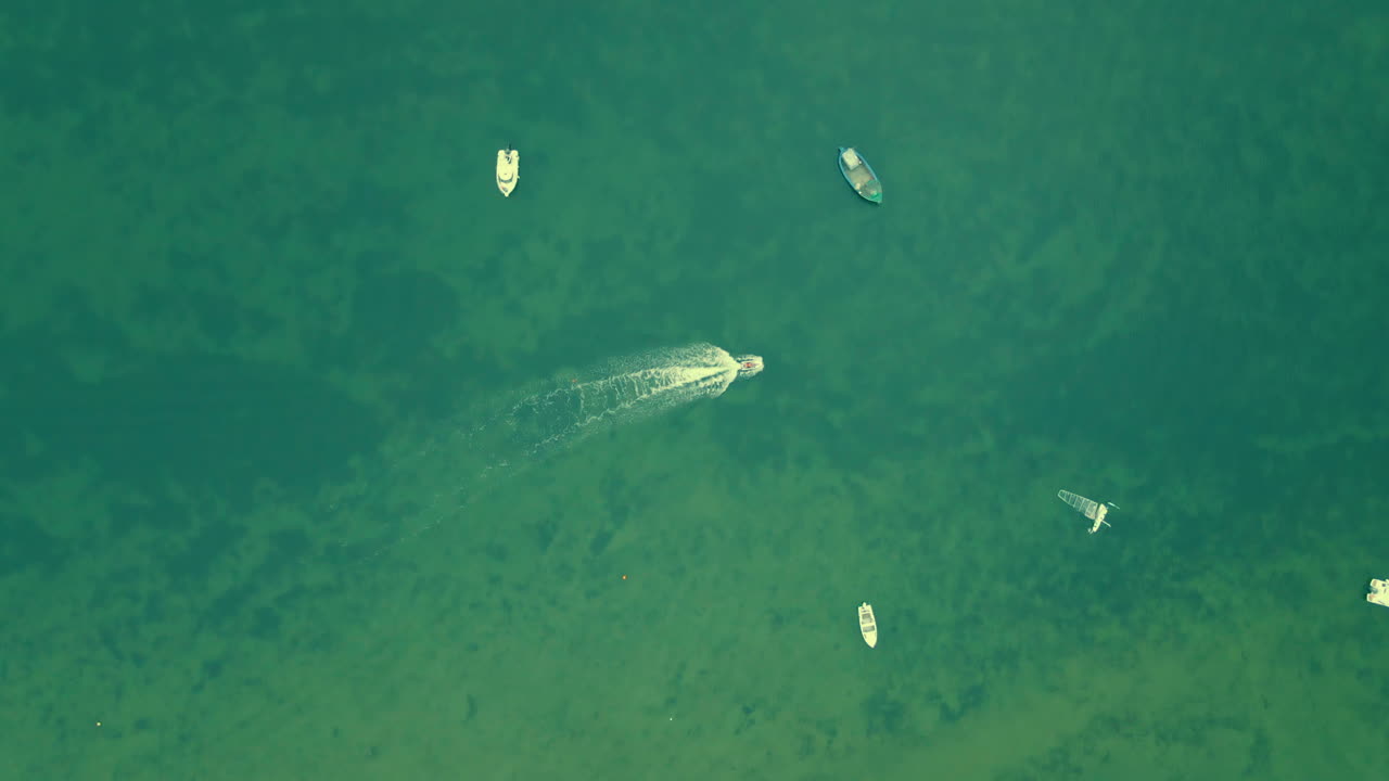 투명한 바다에서 모터보트를 주차하고 운전하는 공중 하향식 샷