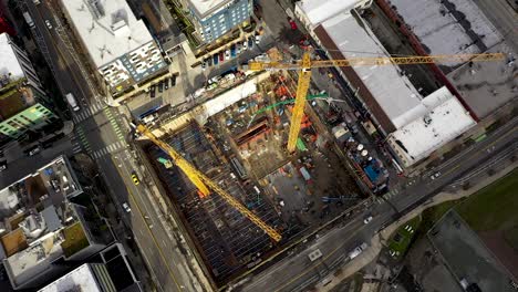 antena aérea de movimiento lento de grúas de construcción sentadas en un lote vacío esperando el desarrollo