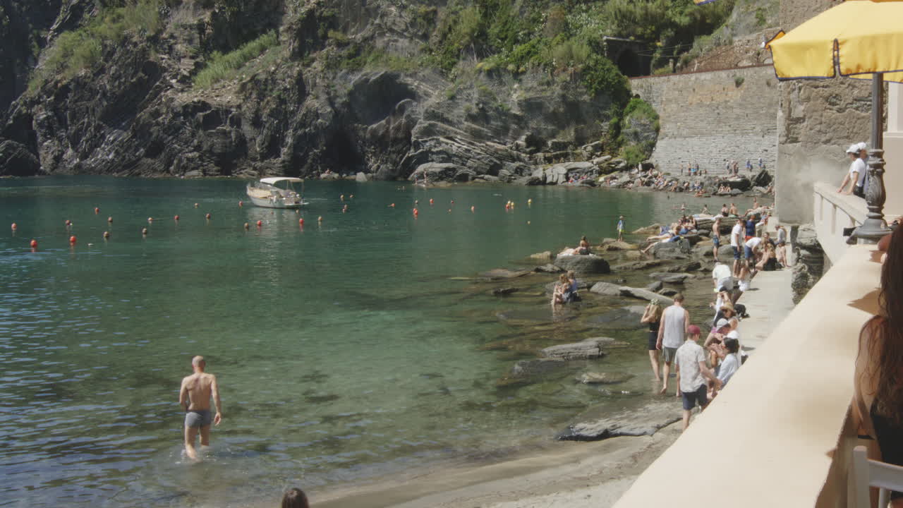 People On The Rocky Shore Of Porto di Vernazza In The Province of La Spezia In Northern Italy. Slow Motion Shot