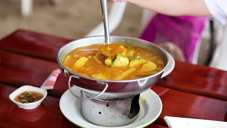 ladling yellow curry into a bowl at table