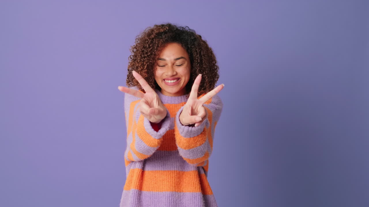 Cheerful Young Woman with Curly Hair Making Peace Sign