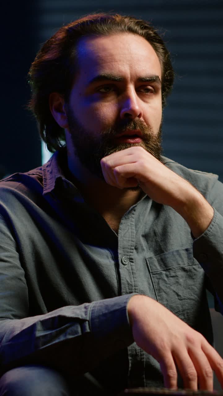 Vertical video Puzzled man eating popcorn while watching confusing movie on TV