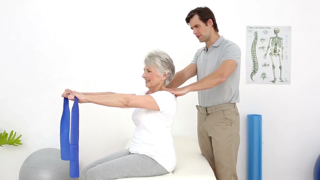 fisioterapeuta comprobando la alineación del hombro de los pacientes con la banda de resistencia