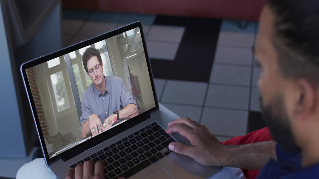 hombre de oriente medio teniendo una videollamada con un colega masculino en una computadora portátil