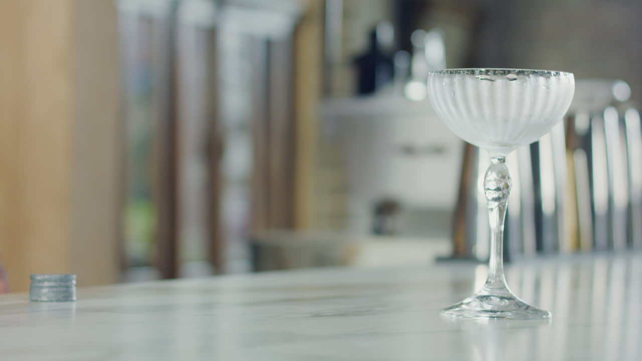 Close-up of a bartender preparing a glass and a crystal to make a cocktail at a bar counter