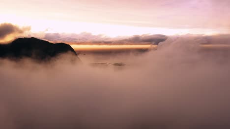 incredibly cinematic shot of mist and clouds above a norwegian fjord during sunset