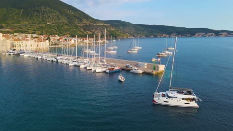 yachts in the bay near the coastal city of croatia against the backdrop of blue skies and blue transparent water, green lush trees and houses with red roofs