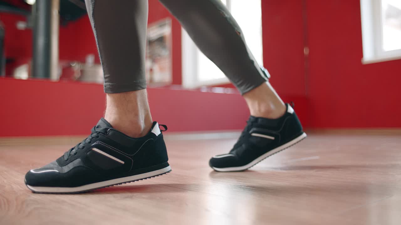 체육 클럽에서 피트니스 트레이닝을 하는 스포츠 신발을 입은 남자 다리의 클로즈업.