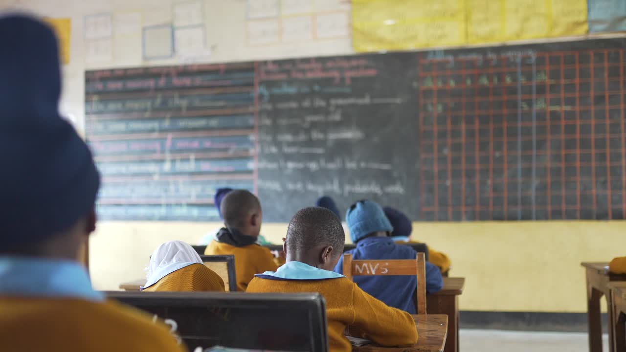 escuela africana con niños haciendo clase mirando la pizarra