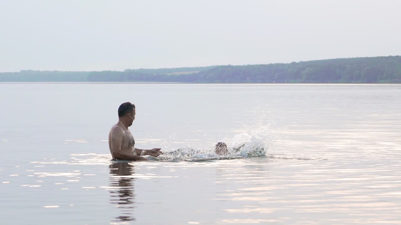 Happy family. Father and son are having fun and splashing in the water. Slow motion.