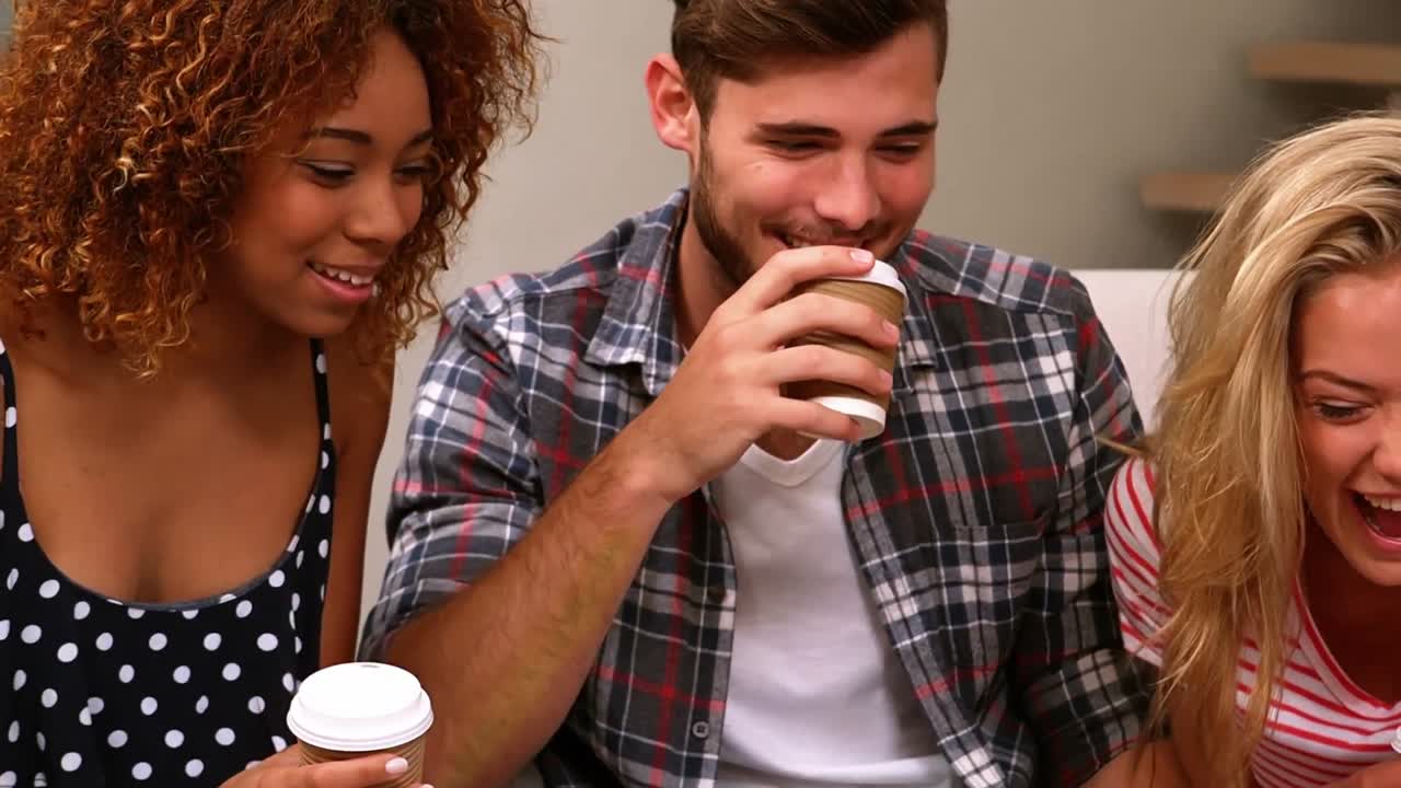 친구 들 이 소파 에 앉아 커피 를 마시며 대화 하고 있다