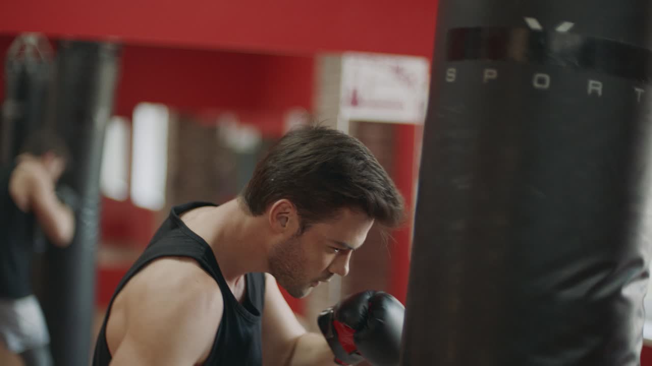 Fitness man training box kick in sport club. Boxer kicking boxing bag in gloves.