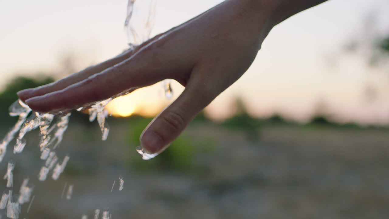 mujer cerca lavando la mano bajo el grifo con agua dulce en tierras de cultivo rurales al amanecer