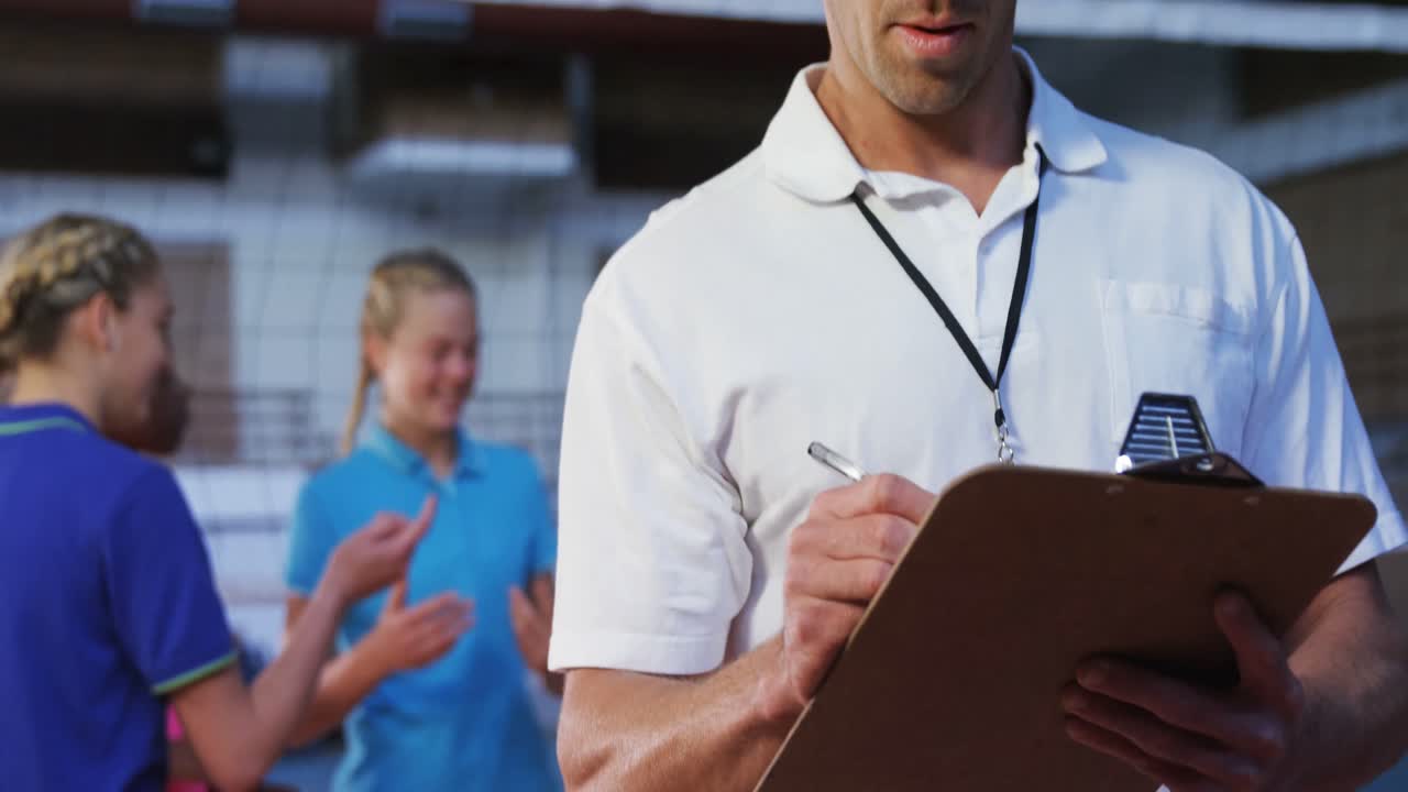 entrenador masculino escribiendo en el clipboard en la cancha 4k