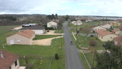 motorcycle drives through france countryside on a cloudy autumn day, drone dolly