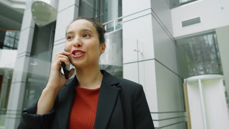 businesswoman walking in office center and talking on phone