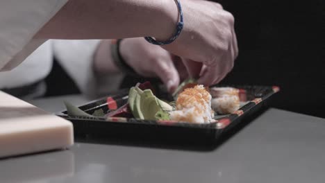 a static shot of sushi and decorative elements being placed on a sushi plate, showcasing the art of sushi presentation. perfect for highlighting food styling and sushi dish arrangements.