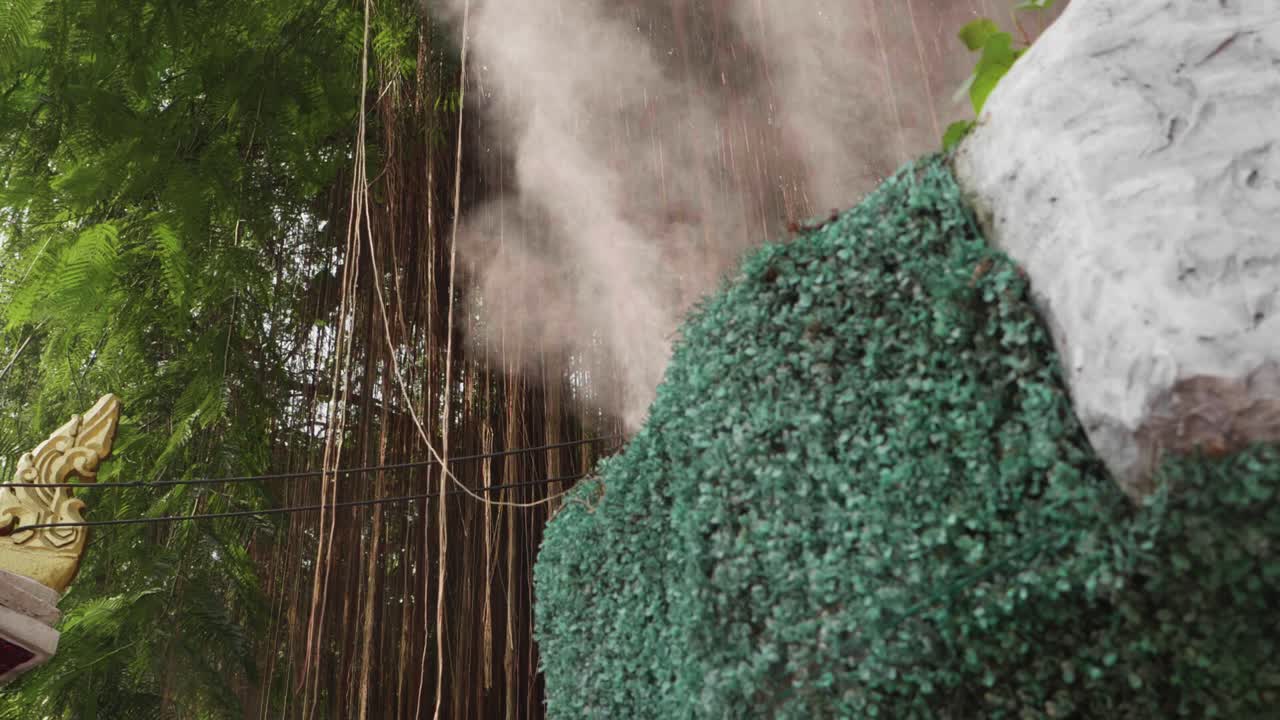 Mist Water Spraying Out of a Teal Colored Bush at the Buddhist Golden Mountain Temple in Thailand.