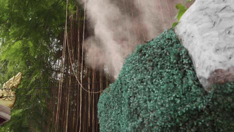 mist water spraying out of a teal colored bush at the buddhist golden mountain temple in thailand.
