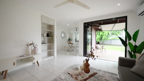 pullback above couch and glass coffee table showcases elegant white living room with door open to outside patio