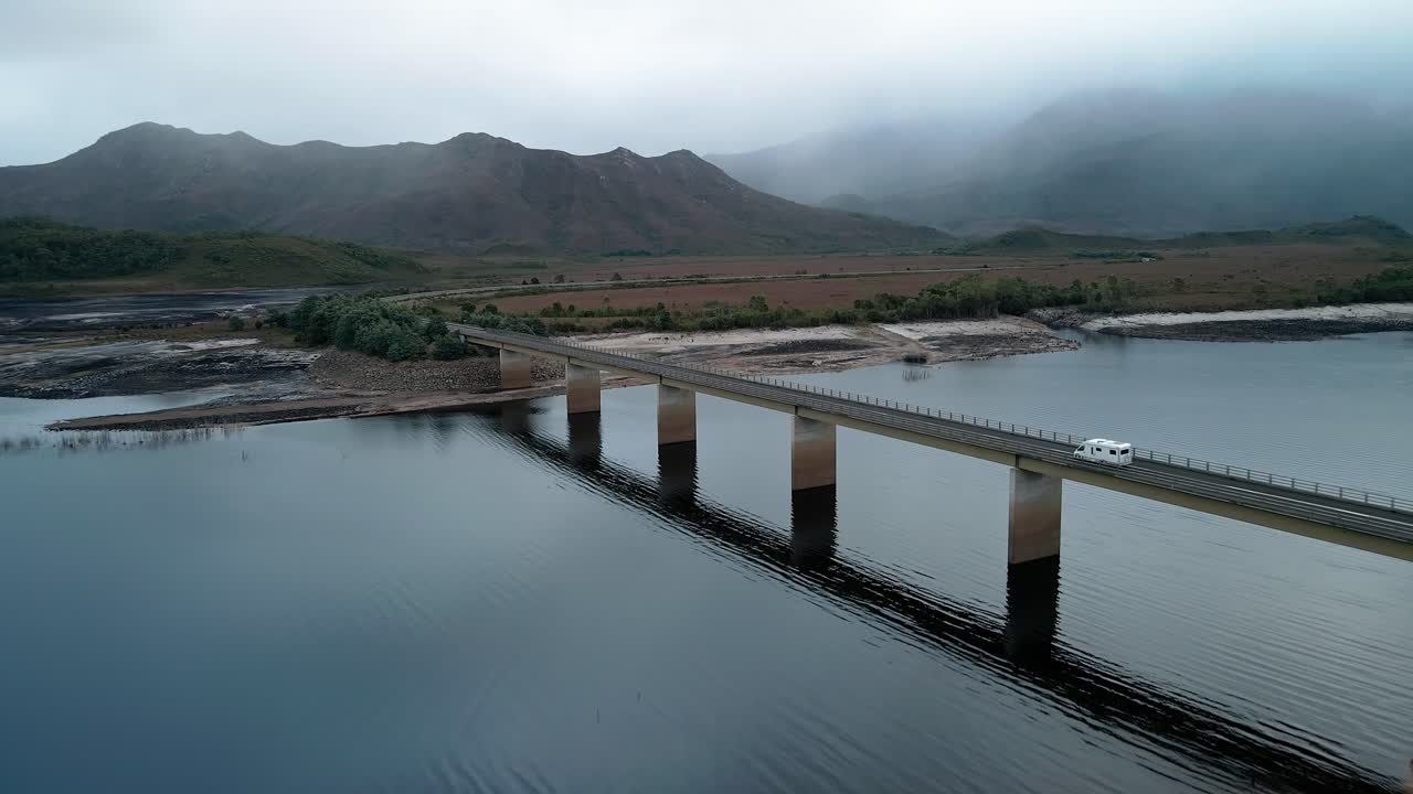 vista aérea delantera del lago burbury con vehículos que pasan por el puente en tasmania, australia en un día de niebla