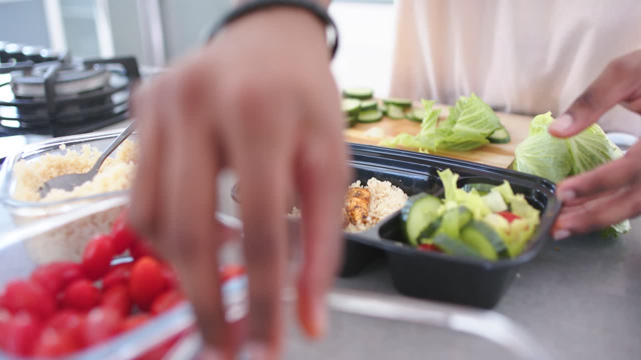 African American man reaching for jar at counter picking chicken placing on rice in tray portioning