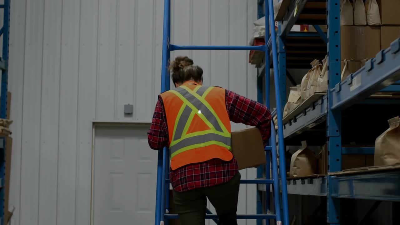 Warehouse worker stepping down ladder carrying box walking aisle, generating network icons overlay