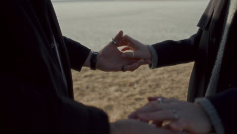 close-up of affectionate couple holding hands in dry grass field