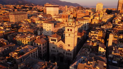 drone orbiting around genoa cathedral in the historical center at sunset, with surrounding old buildings and the cityscape bathed in golden light