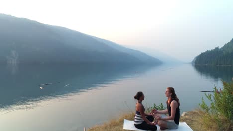 Friends-performing-yoga-near-lakeside-4k