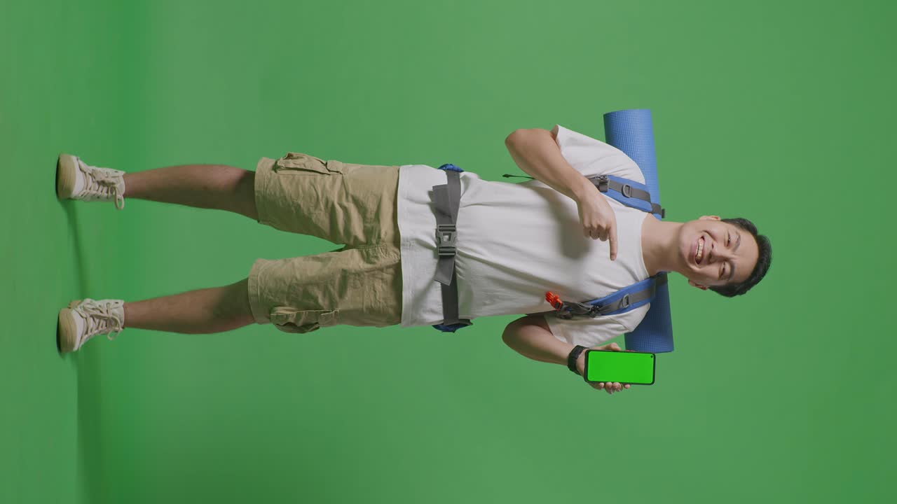 hombre con mochila y teléfono móvil frente a la pantalla verde