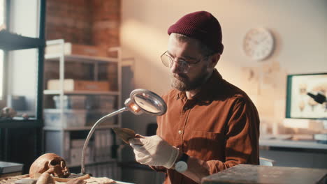 archaeologist inspecting spearhead under magnifying lamp in lab
