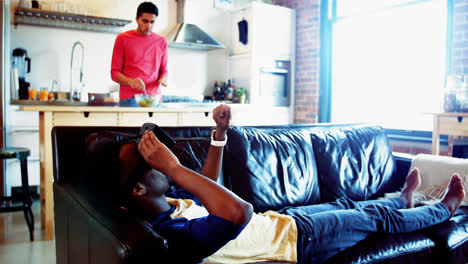 Man-using-virtual-reality-headset-while-friend-preparing-food