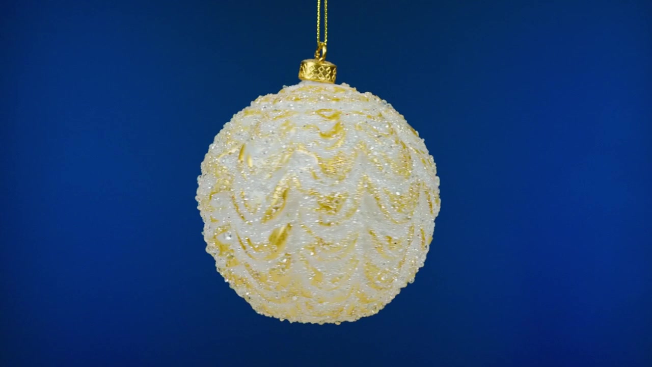 青い背景の上で回転する白とゴールドのクリスマスオーナメント