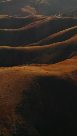 amazingly beautiful smooth brown mountains with no vegetation at the waterfront of the sea. sunlit hills from aerial perspective. vertical video