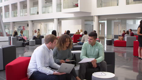 student group studying together in a busy modern university lobby, shot on r3d