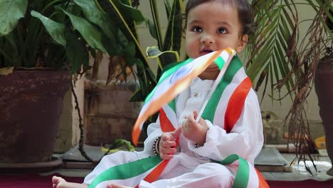 cute toddler waving indian tricolor flag in traditional cloth with innocent facial expression